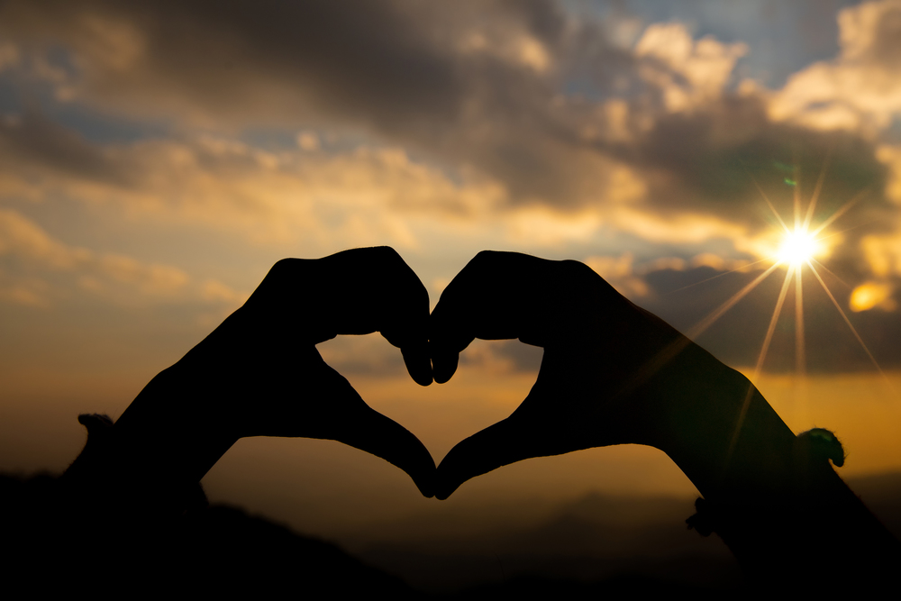 Heart shape from two hand with sunrise background. Freepik.